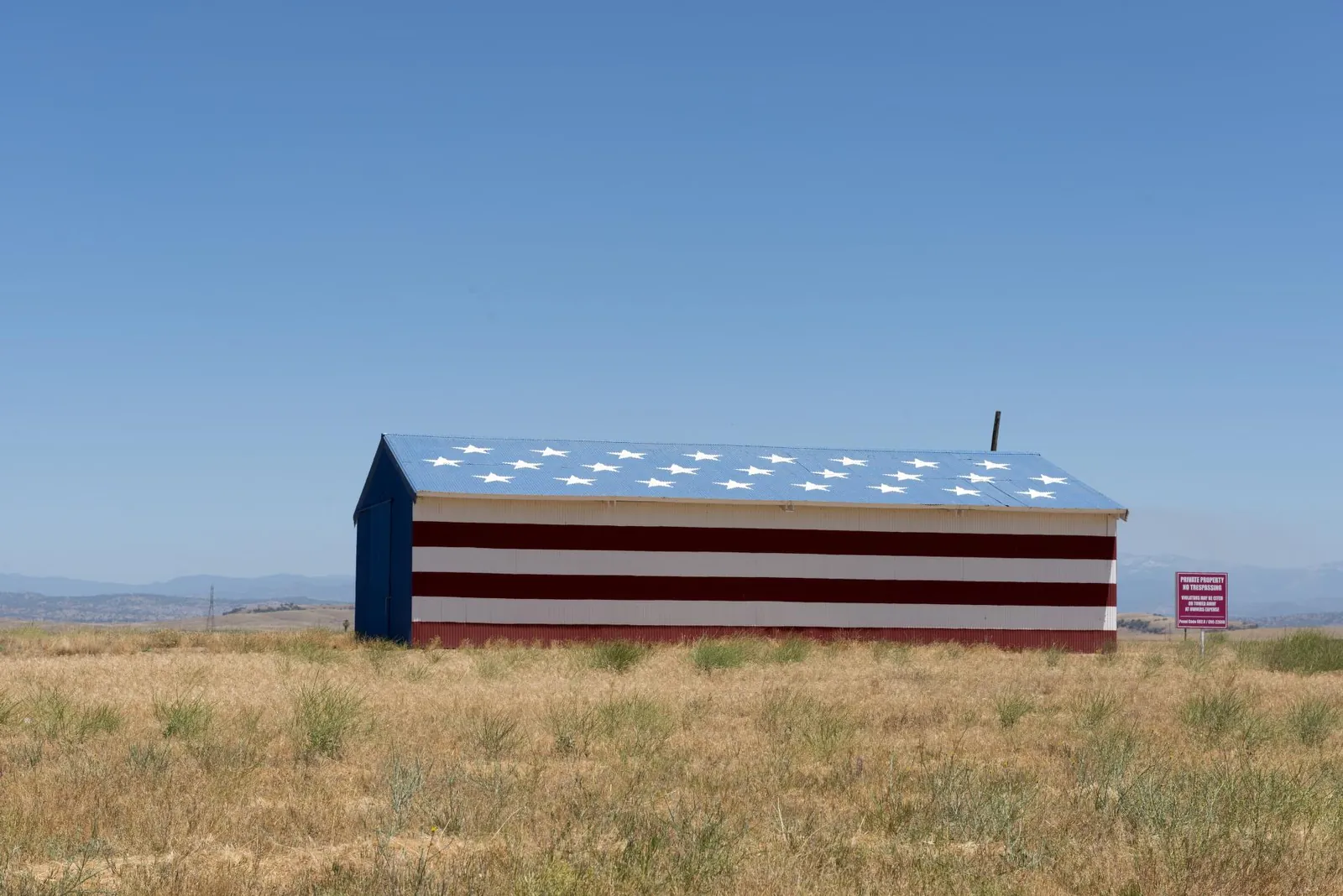 A barn painted as an American flag in a grassy field in Madera, California