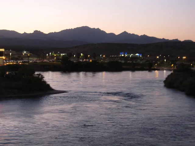 The Colorado River at Bullhead City at dusk, with lights along the bank and mountains behind
