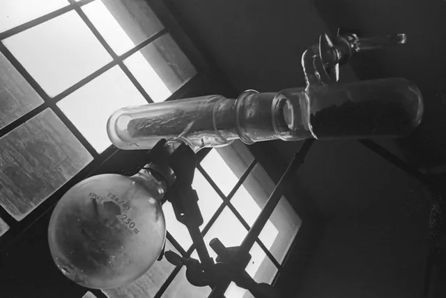 Black-and-white close-up of chemistry lab glassware by a window