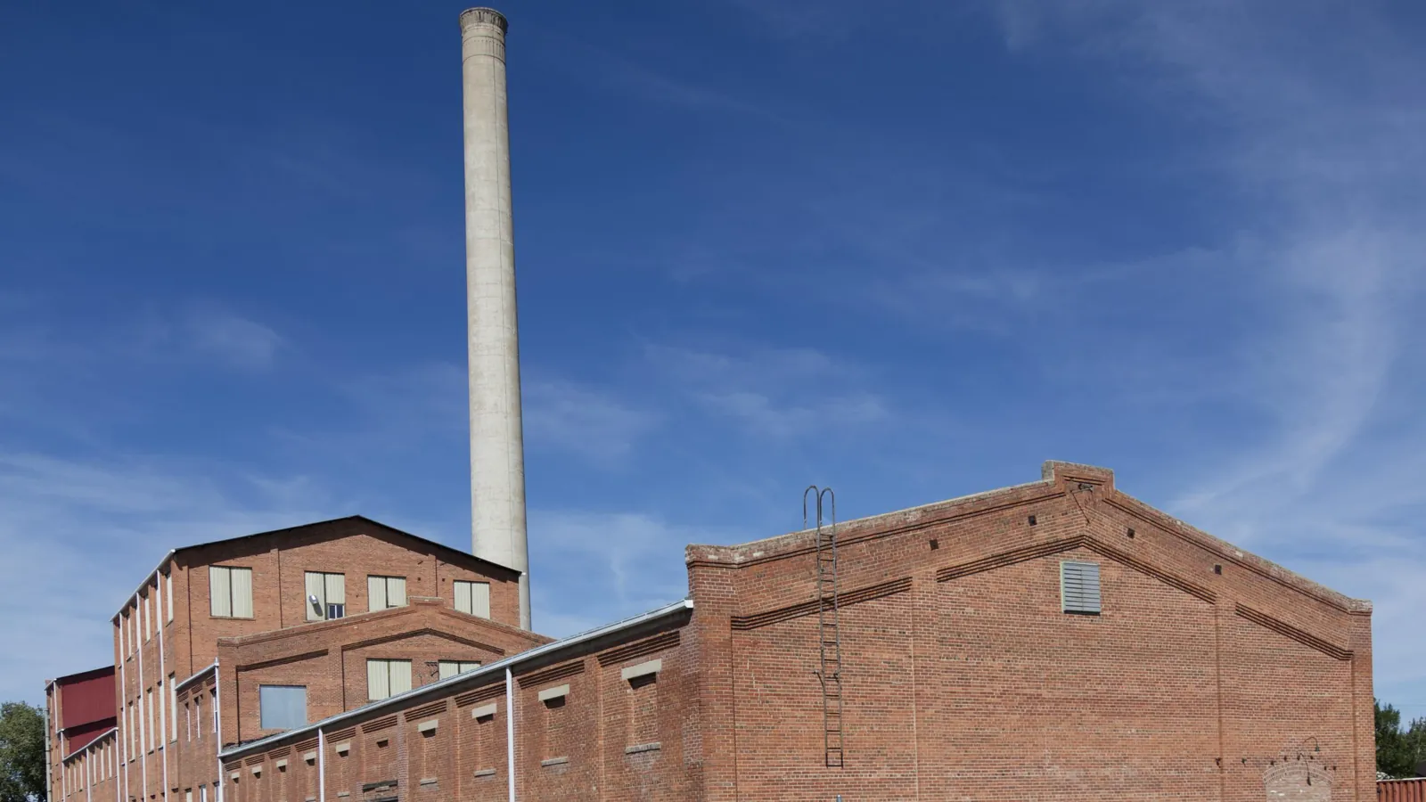 Brick factory building and tall smokestack under a blue sky