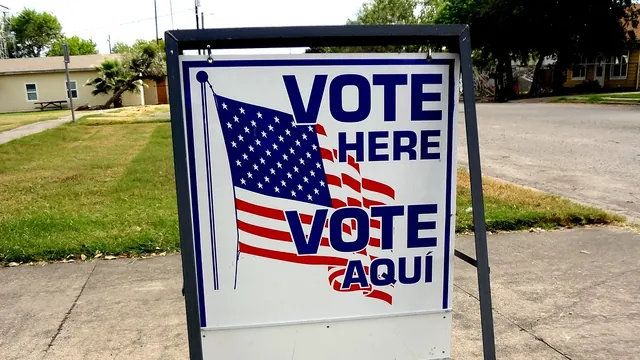 A bilingual Vote Here / Vote Aqui sign on a sidewalk outside a polling place