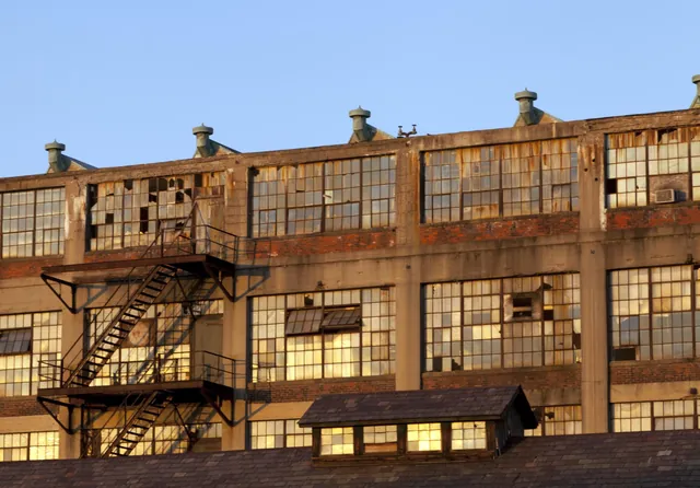 Old brick industrial warehouse with fire escapes in warm light