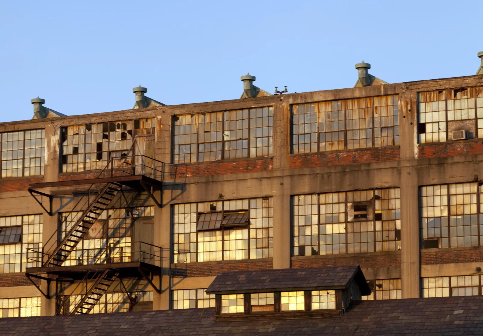 Old brick industrial warehouse with fire escapes in warm light