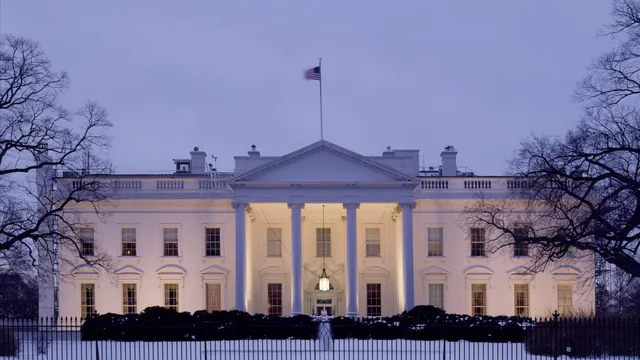The White House lit at dusk behind its iron fence