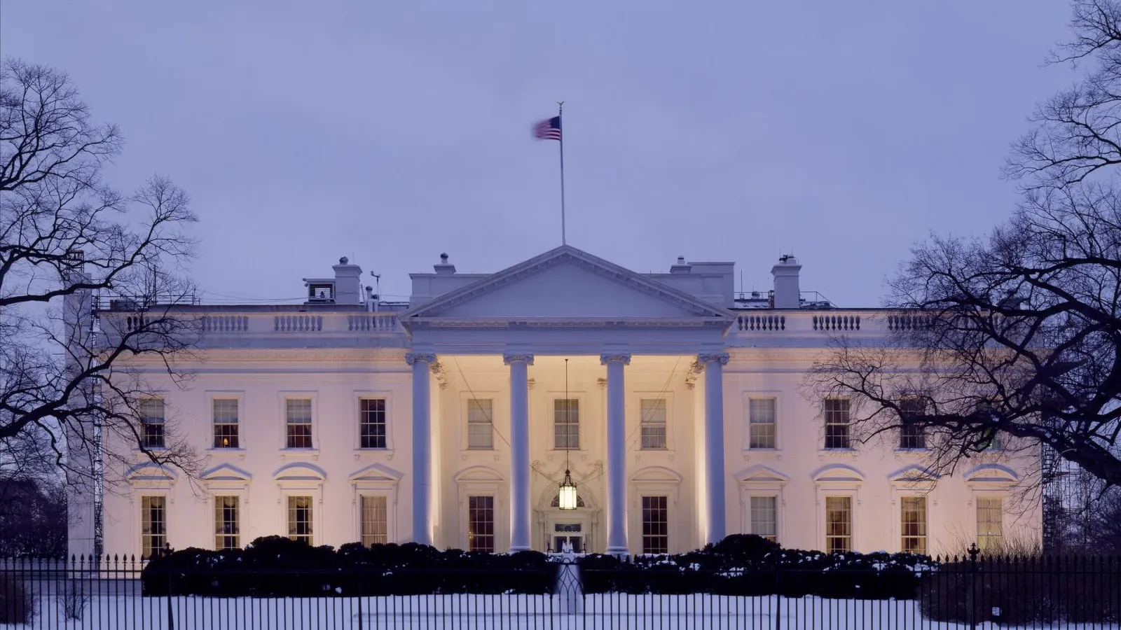 The White House lit at dusk behind its iron fence
